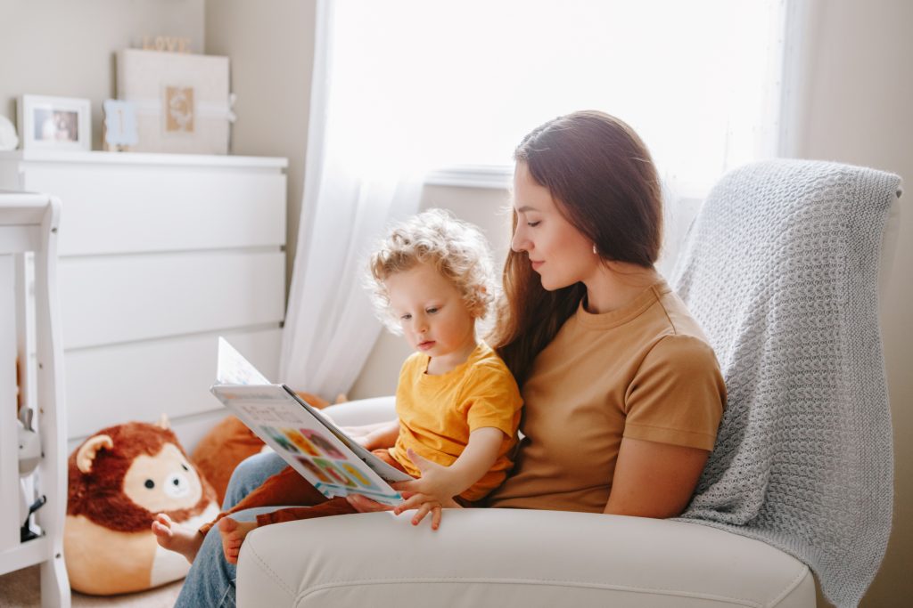 Garde d'enfants à domicile qui lit un livre à un enfant qu'elle garde à Bordeaux