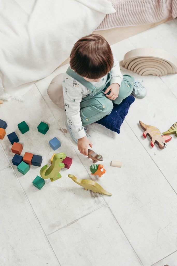 Enfant qui joue avec des jouets colorés au sol